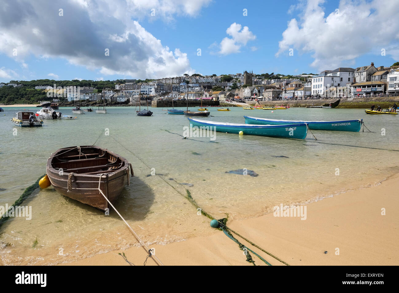 St Ives, Cornwall, UK:  Wooden rowing boat and Gig rowing boats in St Ives harbour with beach in foreground. Stock Photo