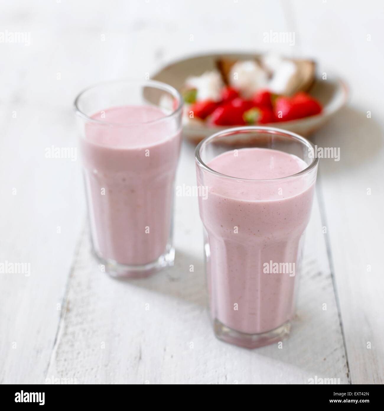 Two glasses of strawberry and macadamia smoothies, ingredients in the background Stock Photo