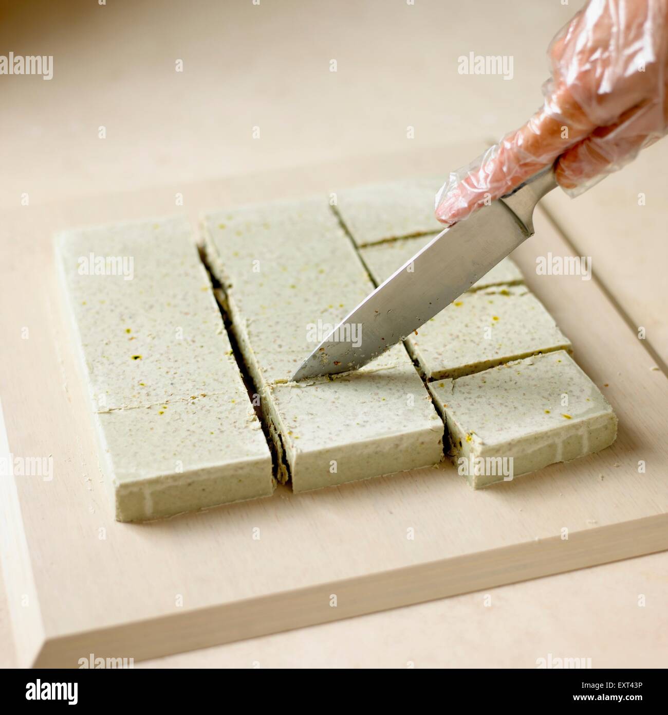 Cutting large block of home-made rosemary soap into individual bars Stock Photo