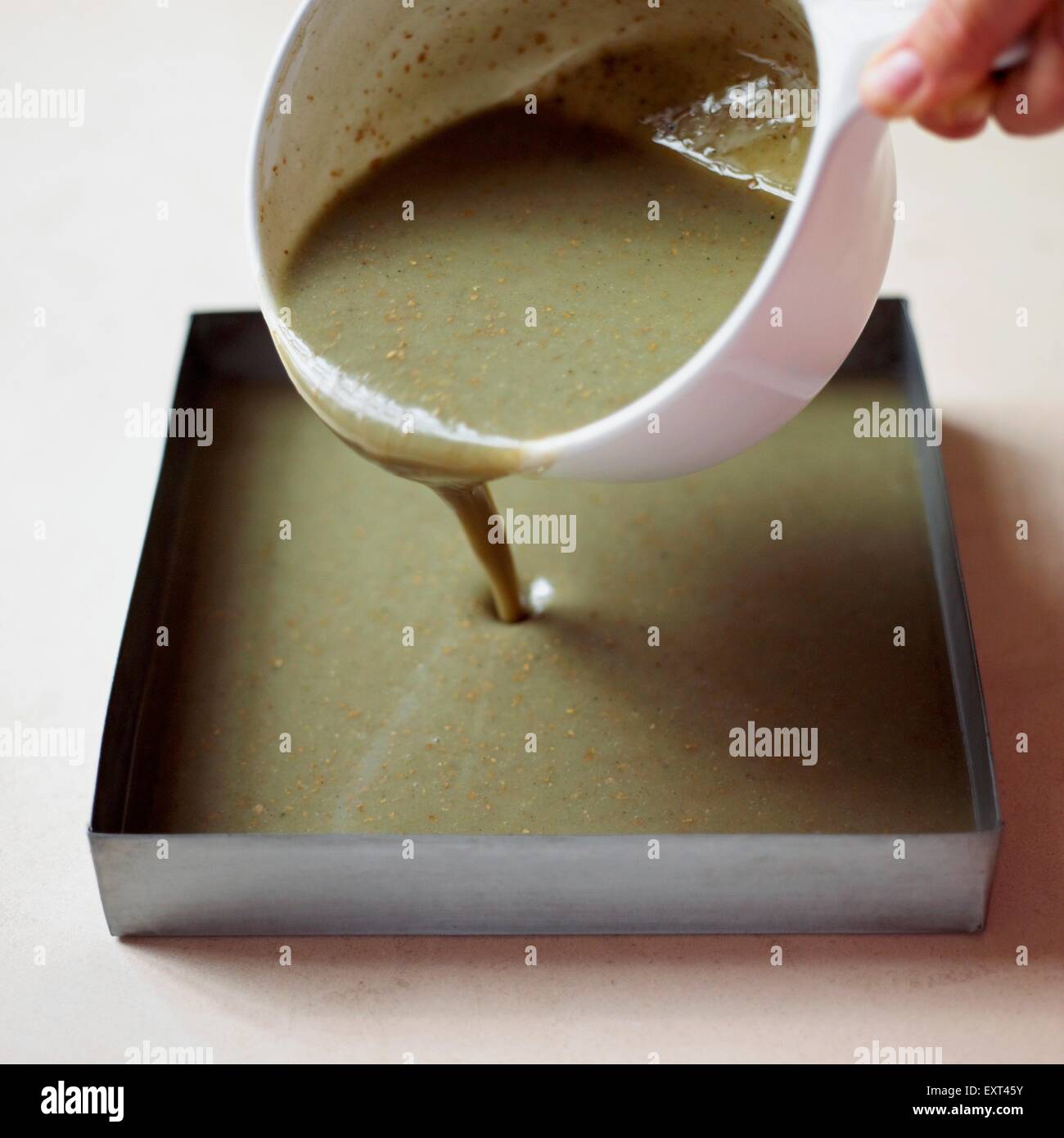 Pouring melted soap mixture into square container Stock Photo