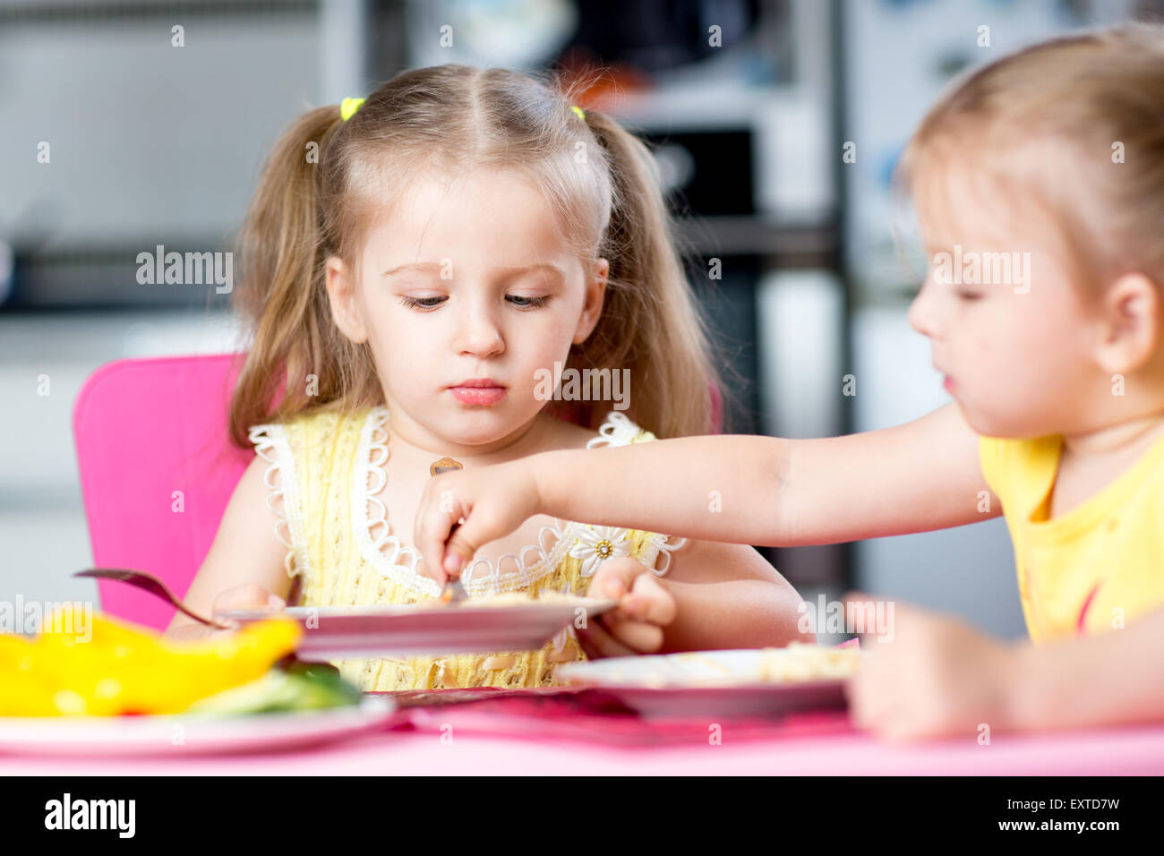 children eat spaghetti with vegetables in nursery Stock Photo