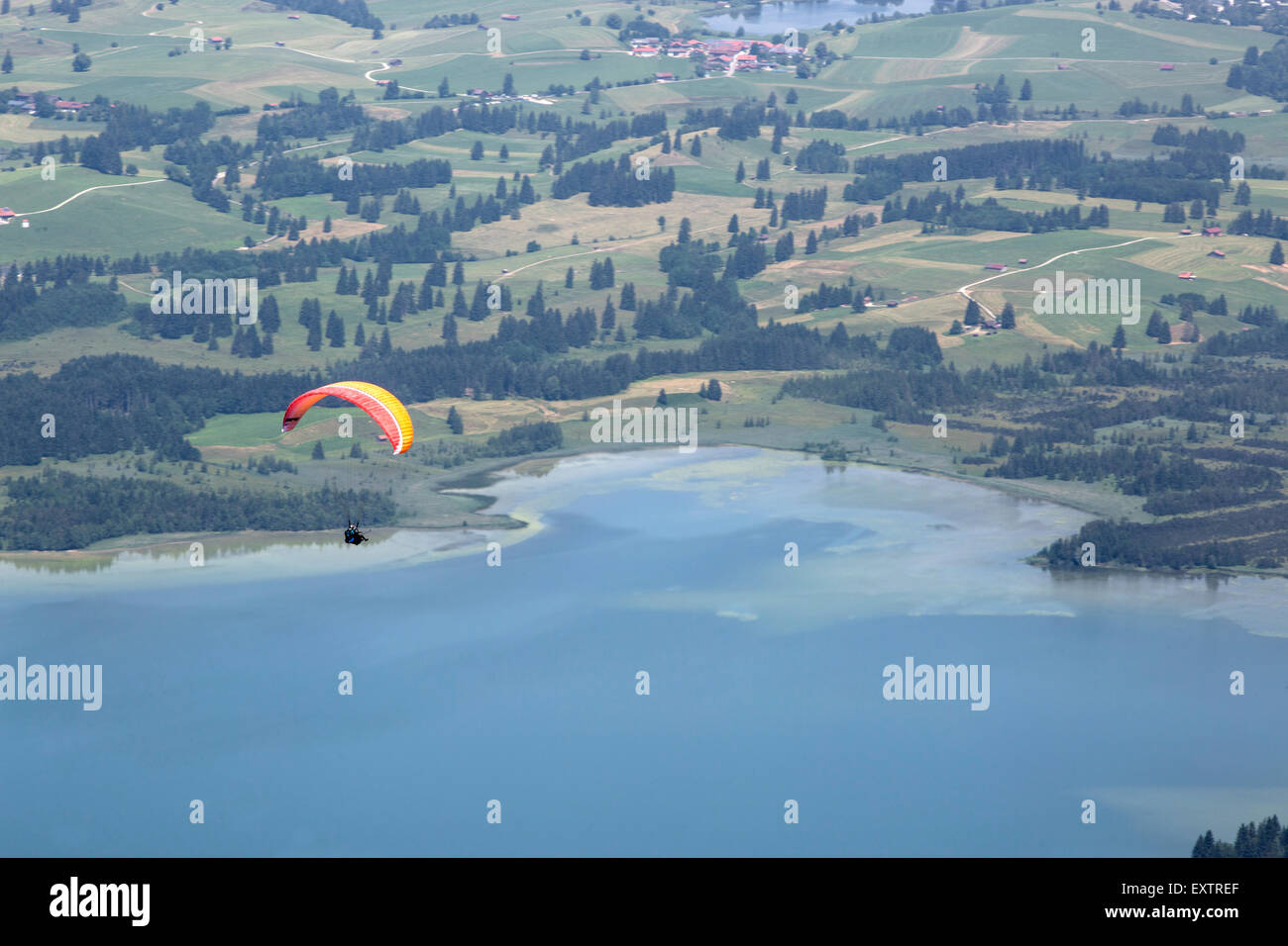 Paragliders flying over lake Forggensee in Bavarian mountains Stock Photo