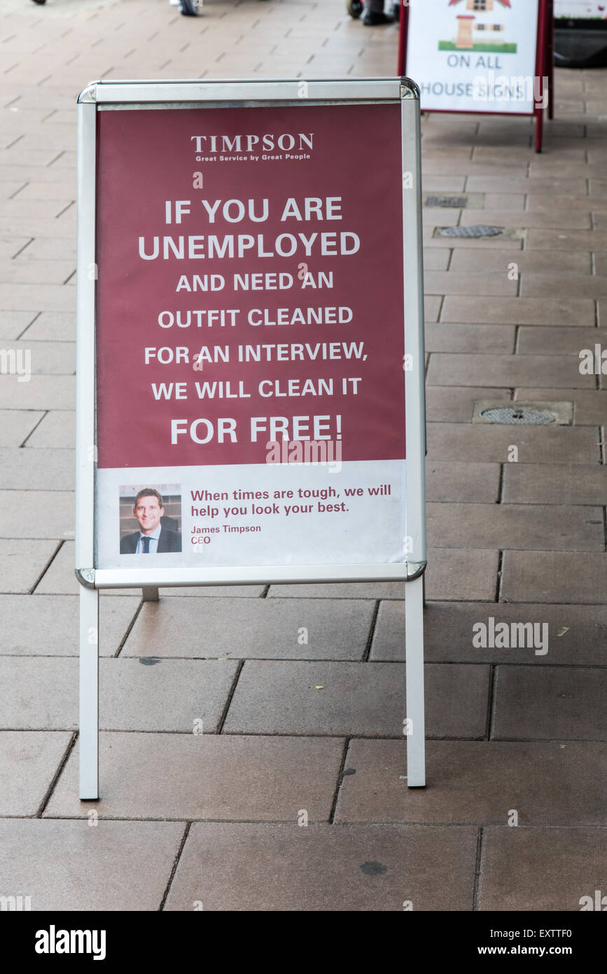 Sign outside a Timpsons store in Exmouth Devon indicating that they will dry clean an outfit for an unemployed person for free. Stock Photo