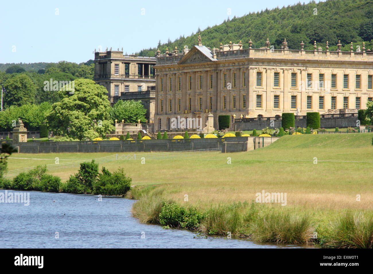 Chatsworth House seen from the banks of the River Derwent on a glorious summer day, Peak District, Derbyshire UK Stock Photo