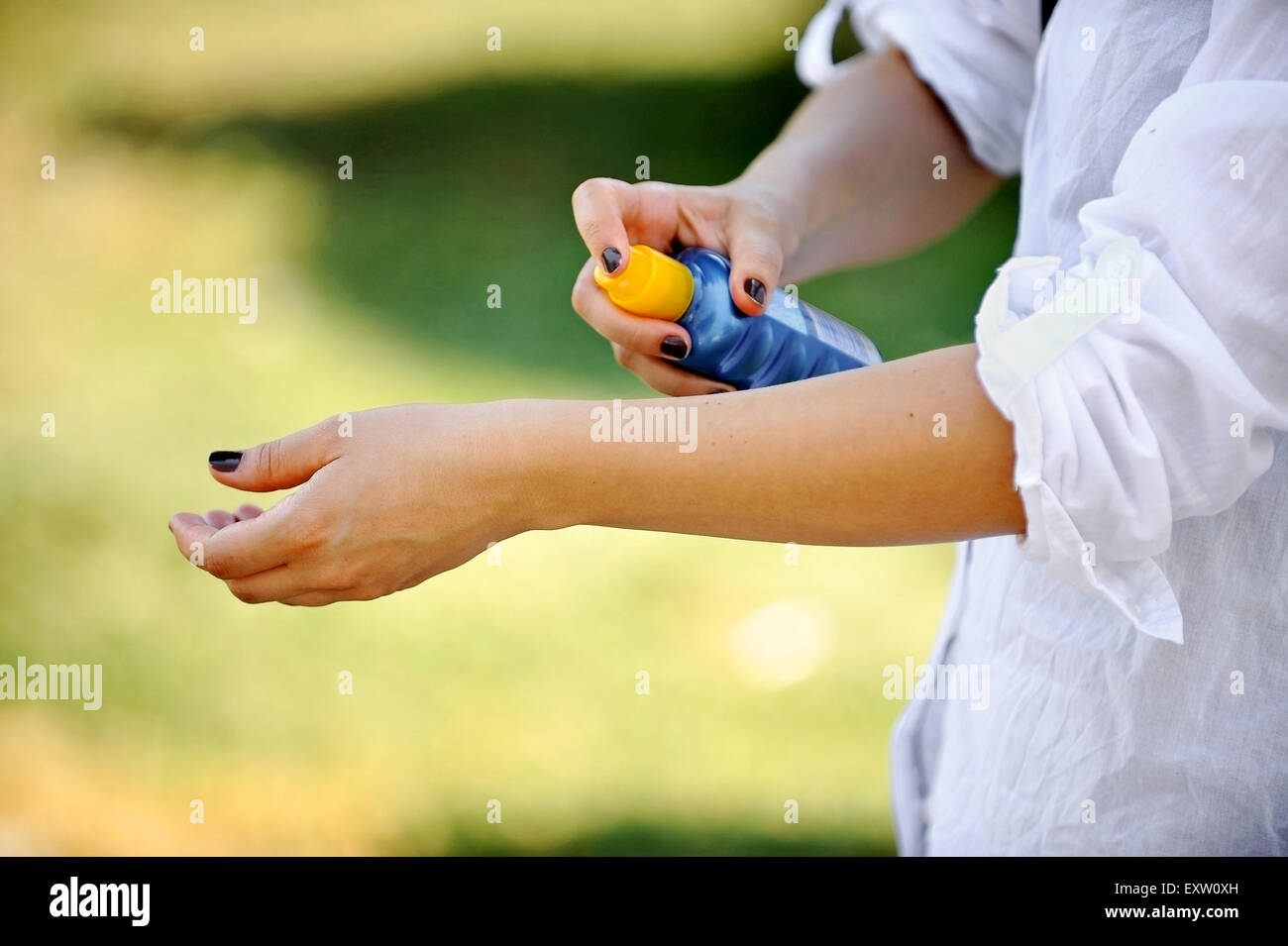 Hands of a woman using a blue bottle of sunscreen Stock Photo