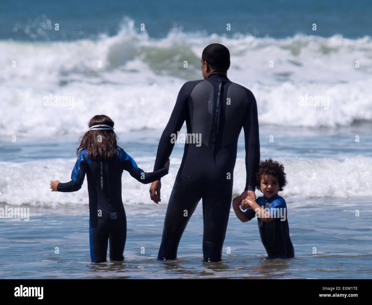Father and children playing in the sea together, Woolacombe, Devon, UK Stock Photo