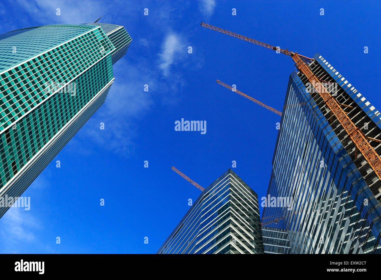 Uncompleted high-rise buildings with cranes against blue sky. Stock Photo
