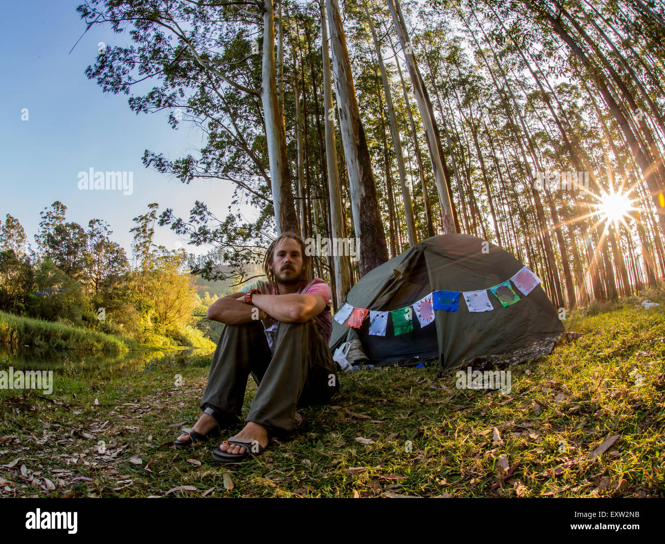 happy man on vacation, sitting in front of his tent in the forest Stock Photo