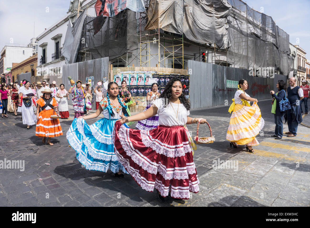 pretty Mexican indigenous women wearing brightly colored traditional costumes take part in parade in historic center of Oaxaca Stock Photo