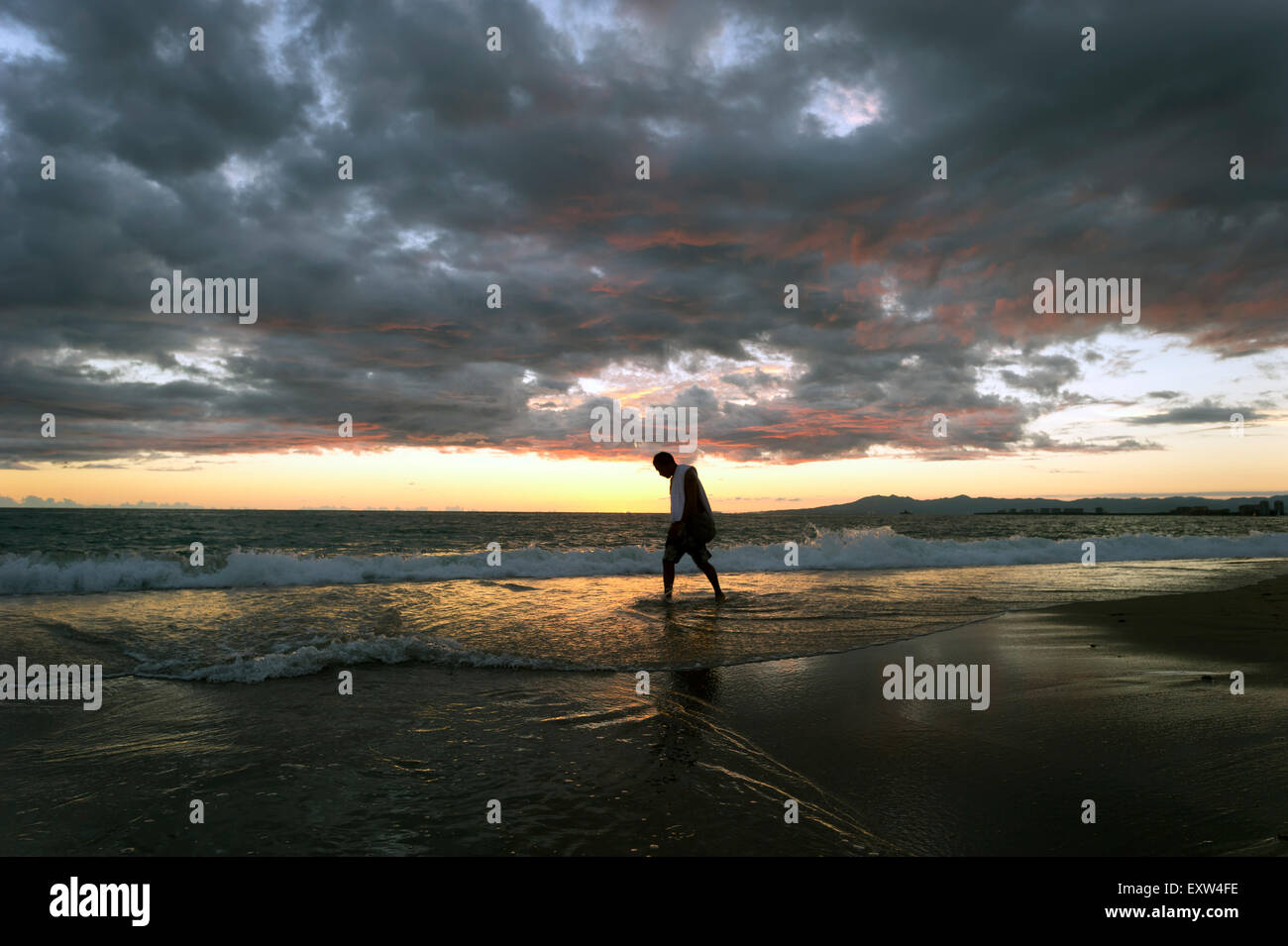 Solitude man walking alone on beach at sunset. Stock Photo