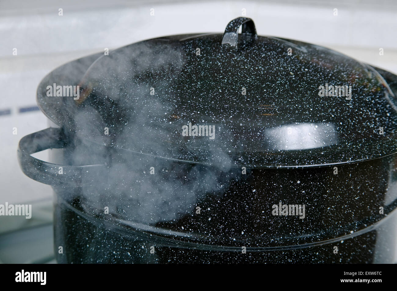 Large blue pot of boiling water, with the steam making the lid rise