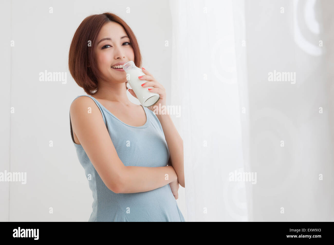 Young woman holding a bottle of milk and smiling at the camera, Stock Photo
