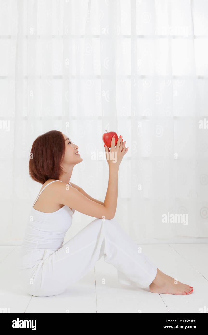 Young woman sitting on the floor and holding an apple, Stock Photo