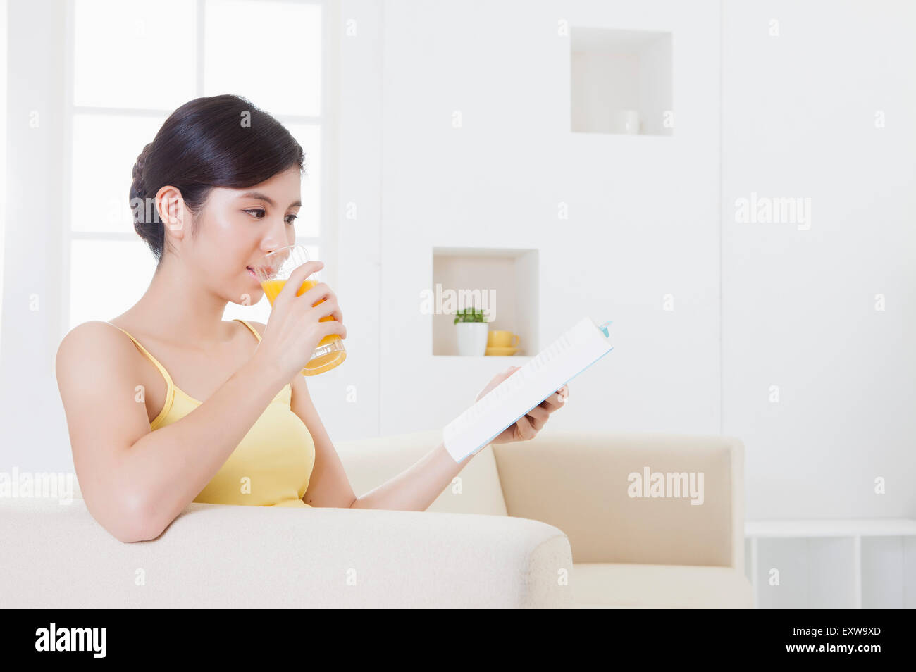 Young woman drinking juice and reading a book, Stock Photo