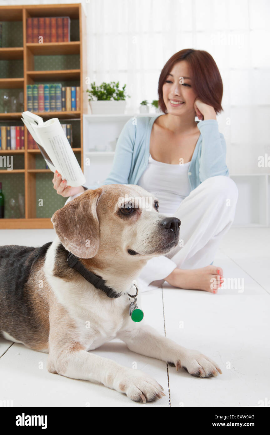 Young woman sitting with her dog and reading a book, Stock Photo