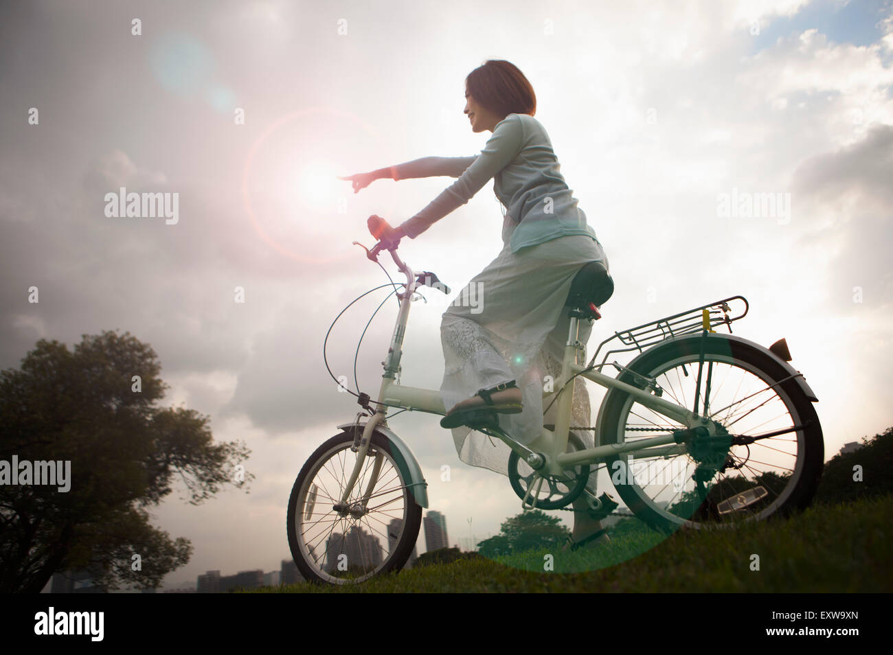 Young woman riding a bike and pointing away, Stock Photo