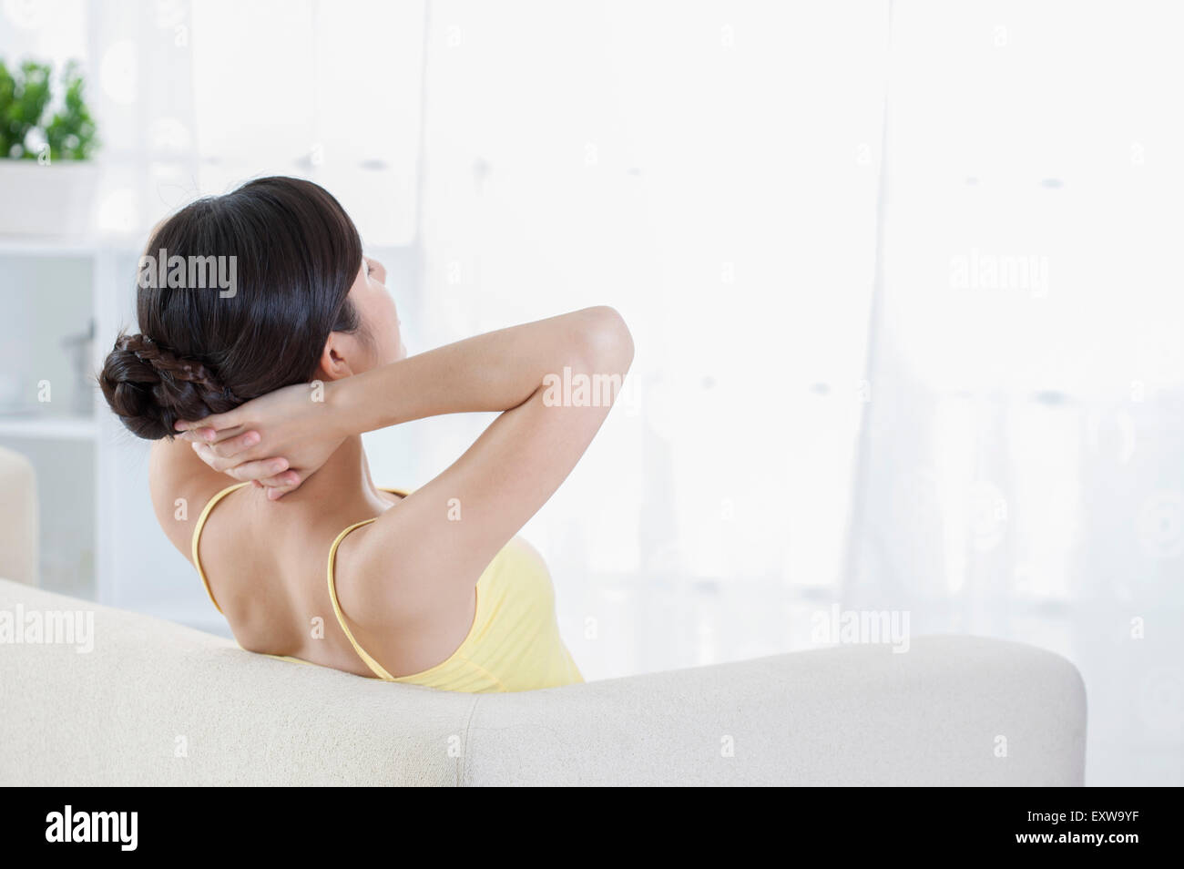 Young woman sitting with hands behind head, Stock Photo