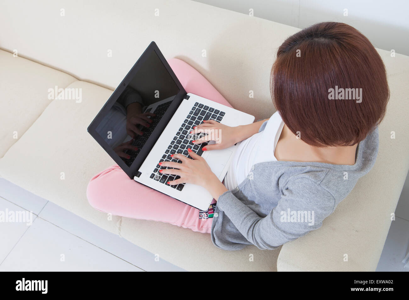 Young woman sitting on the sofa and using laptop Stock Photo - Alamy