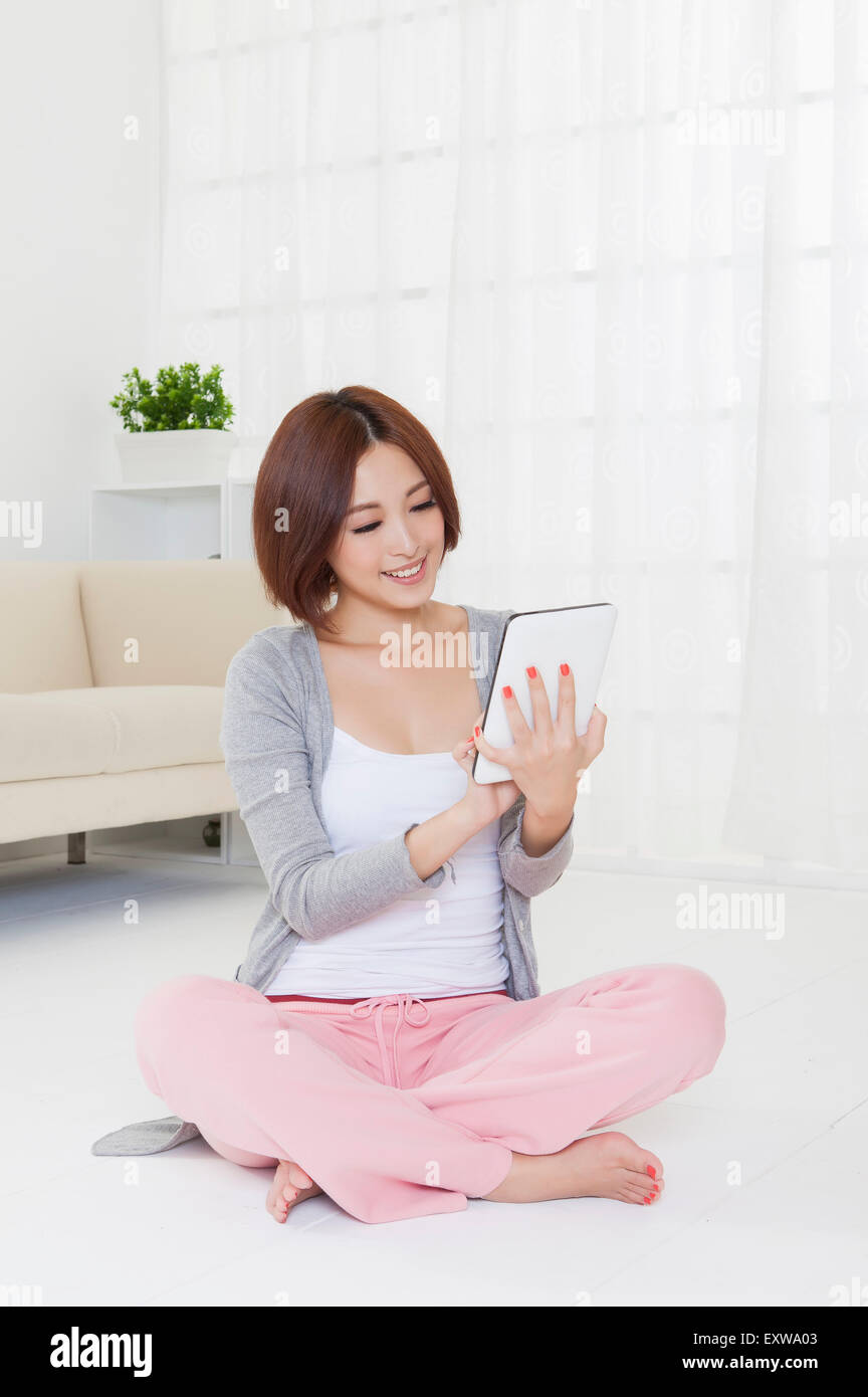 Young woman holding touch pad and looking down with smile, Stock Photo