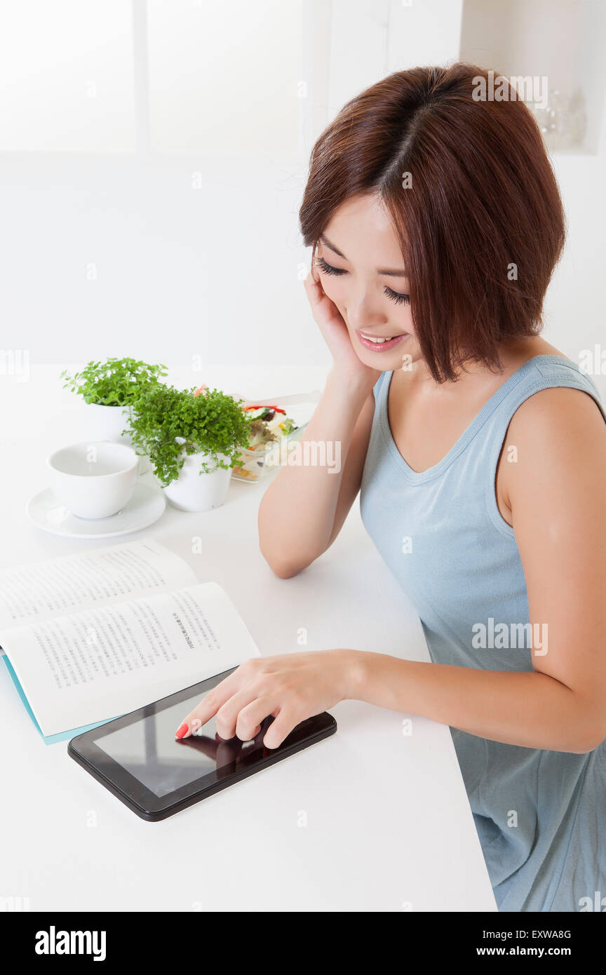 Young woman reading book and touching note pad, Stock Photo