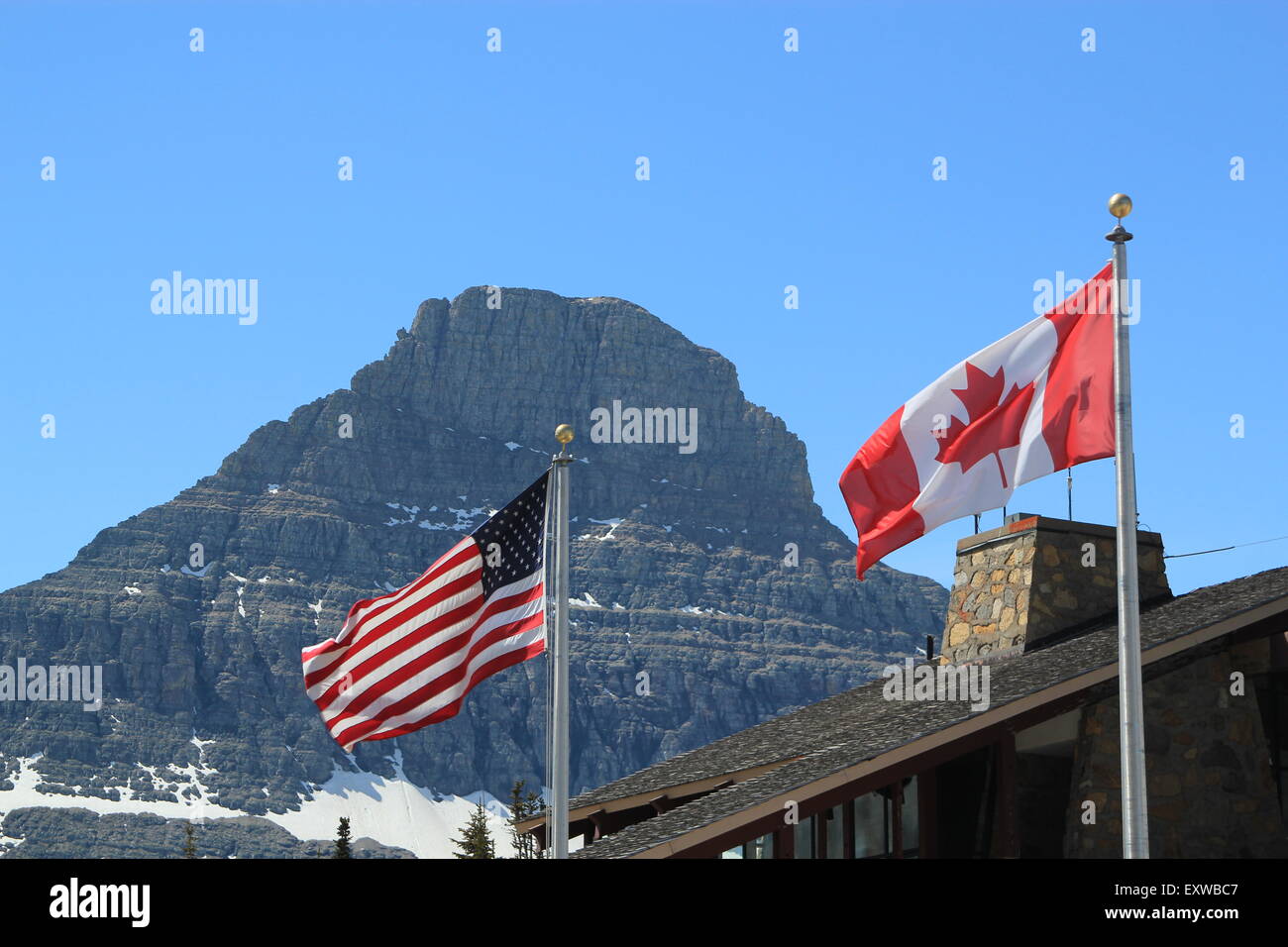 American and Canadian flags, showing the full stars and stripes and maple leaf respectively, on silver flagpoles Stock Photo