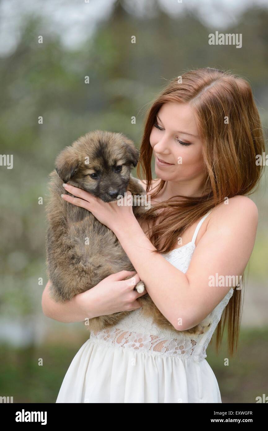 Young woman with a mixed breed dog puppy in garden Stock Photo