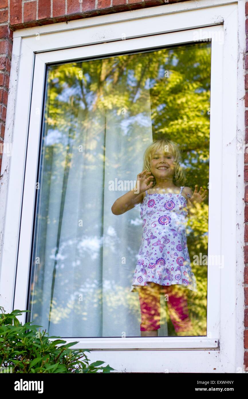 Girl standing at window Stock Photo