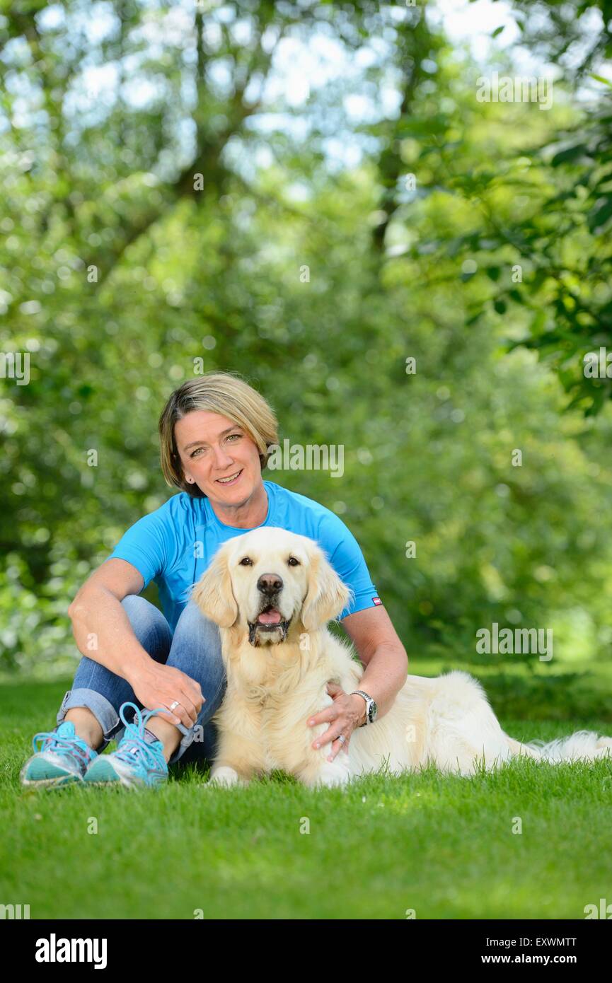 Mature woman with a golden retriever in garden Stock Photo