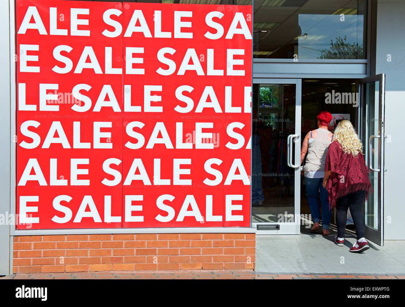 Peacocks store holding a sale, as two young women walk inside, England UK Stock Photo