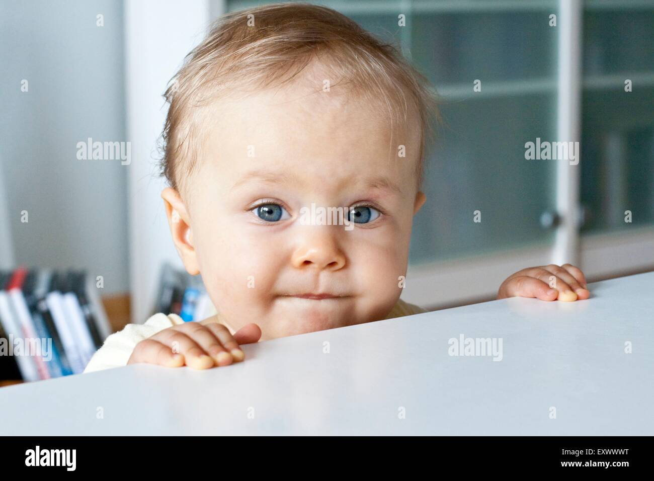 Baby gripping at table Stock Photo