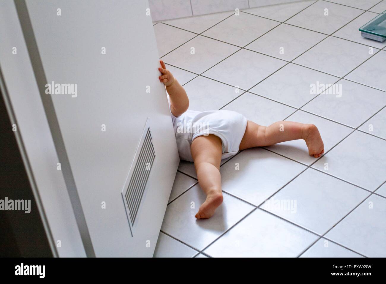 Baby playing with bathroom door Stock Photo