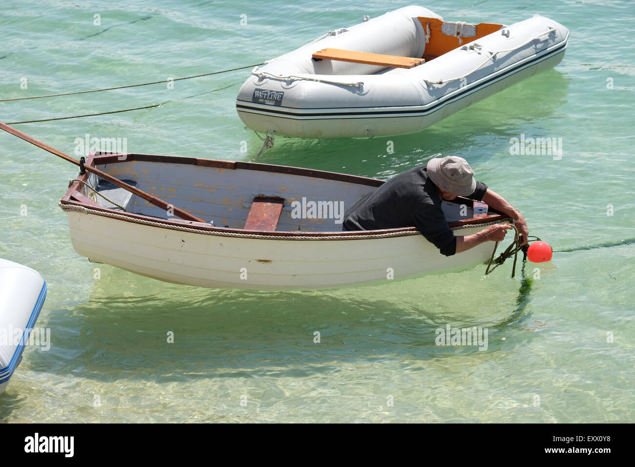 St Ives, Cornwall, UK:  Man in Rowing Boat untying rope in St Ives Harbour. Stock Photo