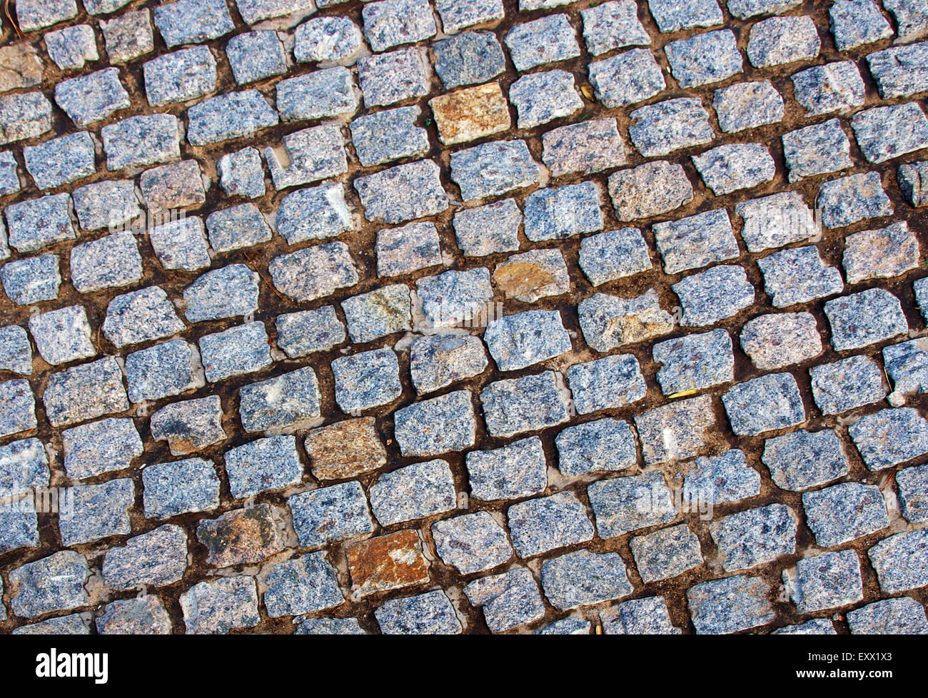 Old road pavement of the small rough granite tiles close up Stock Photo