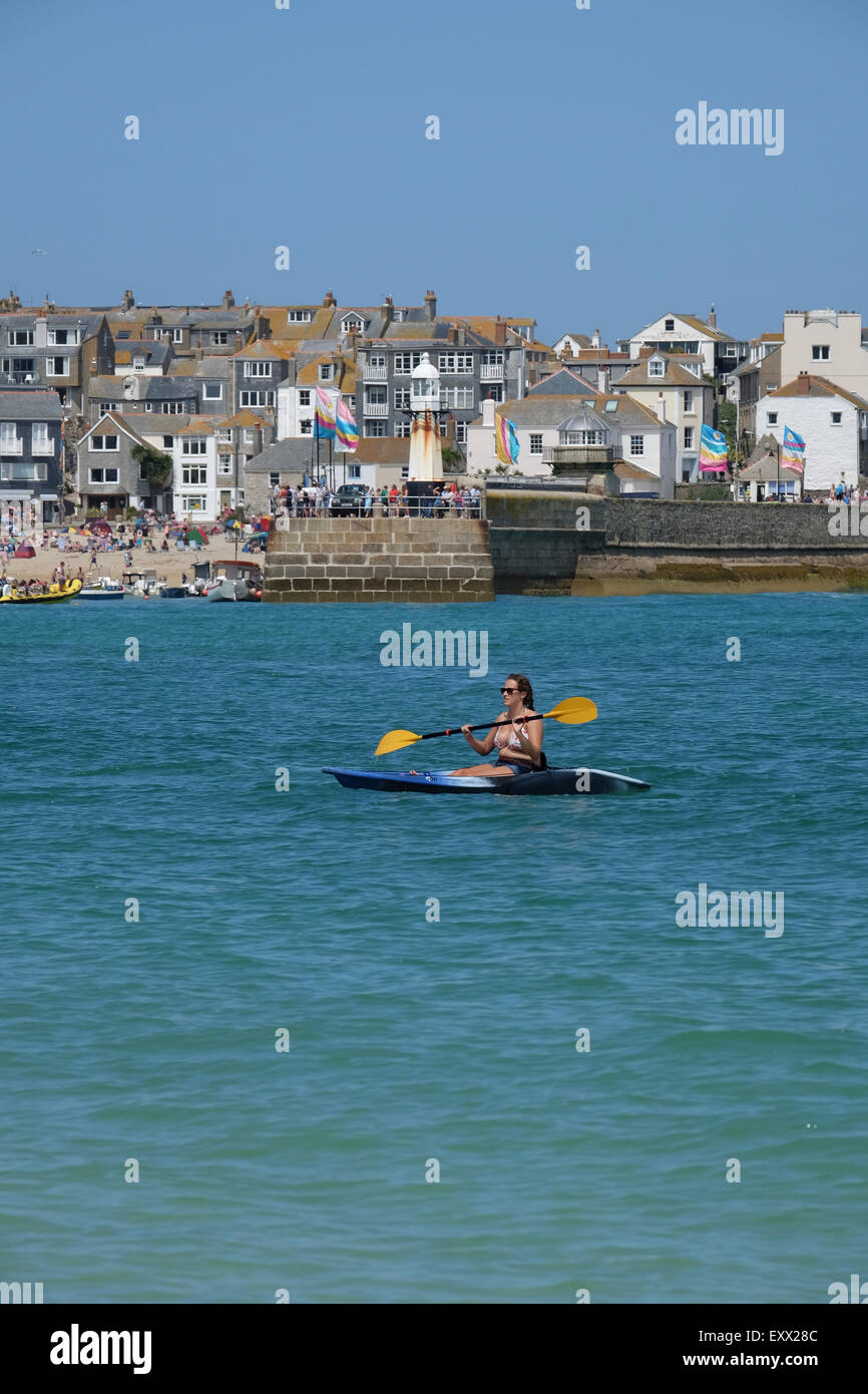 St Ives, Cornwall, UK:  Woman in Kayak enjoying the water off Porthminster beach with St Ives in the background. Stock Photo