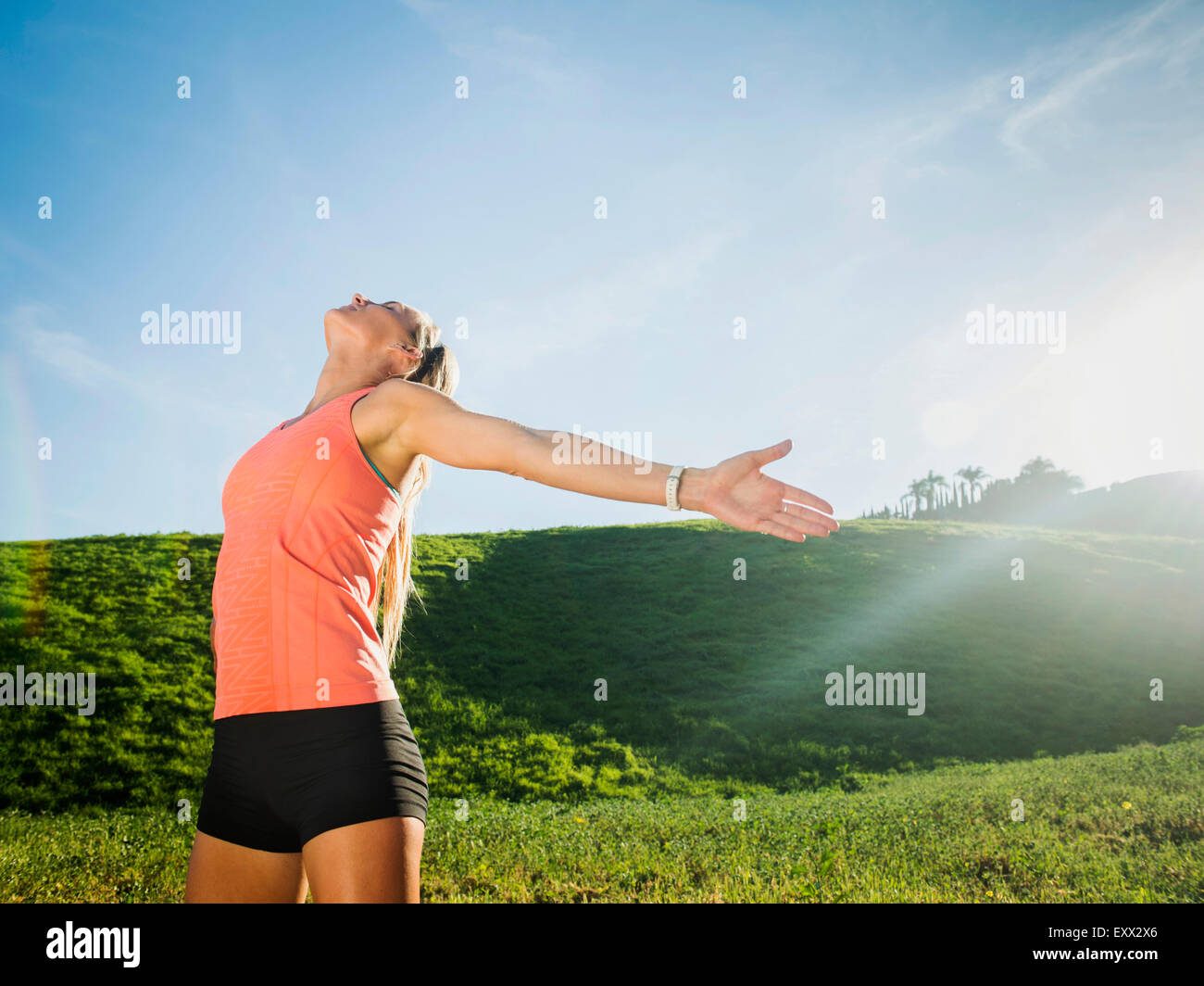 Woman with outstretched arms in field Stock Photo