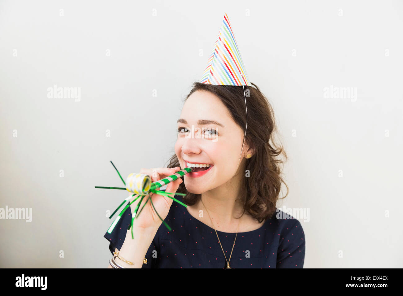 Young woman blowing party horn hi-res stock photography and images - Alamy