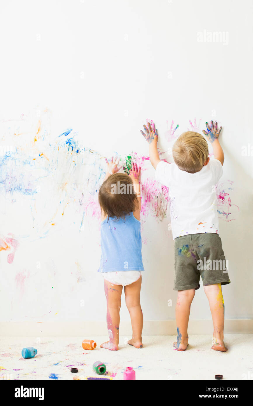 Children (2-3) painting on wall, rear view Stock Photo