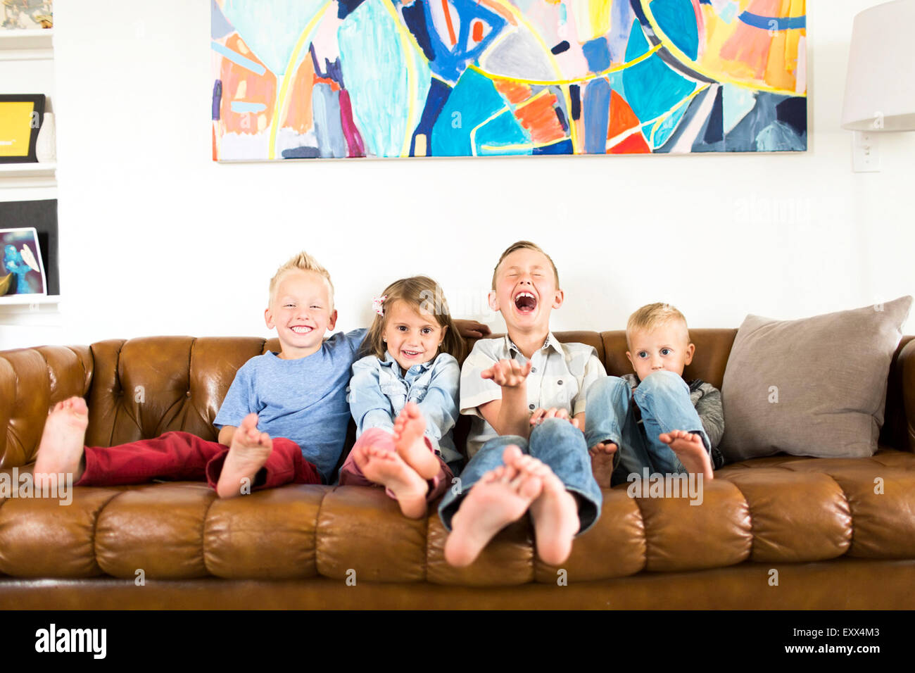 Smiling children (2-3, 4-5, 6-7) sitting on sofa Stock Photo