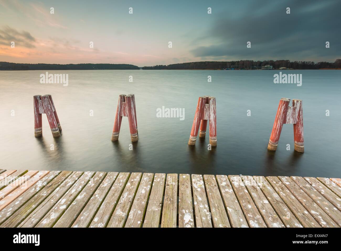 Beautiful lake landscape with jetty. Long time exposure photo with filter. Polish lake shore at cloudy weather sunset. Dramatic  Stock Photo