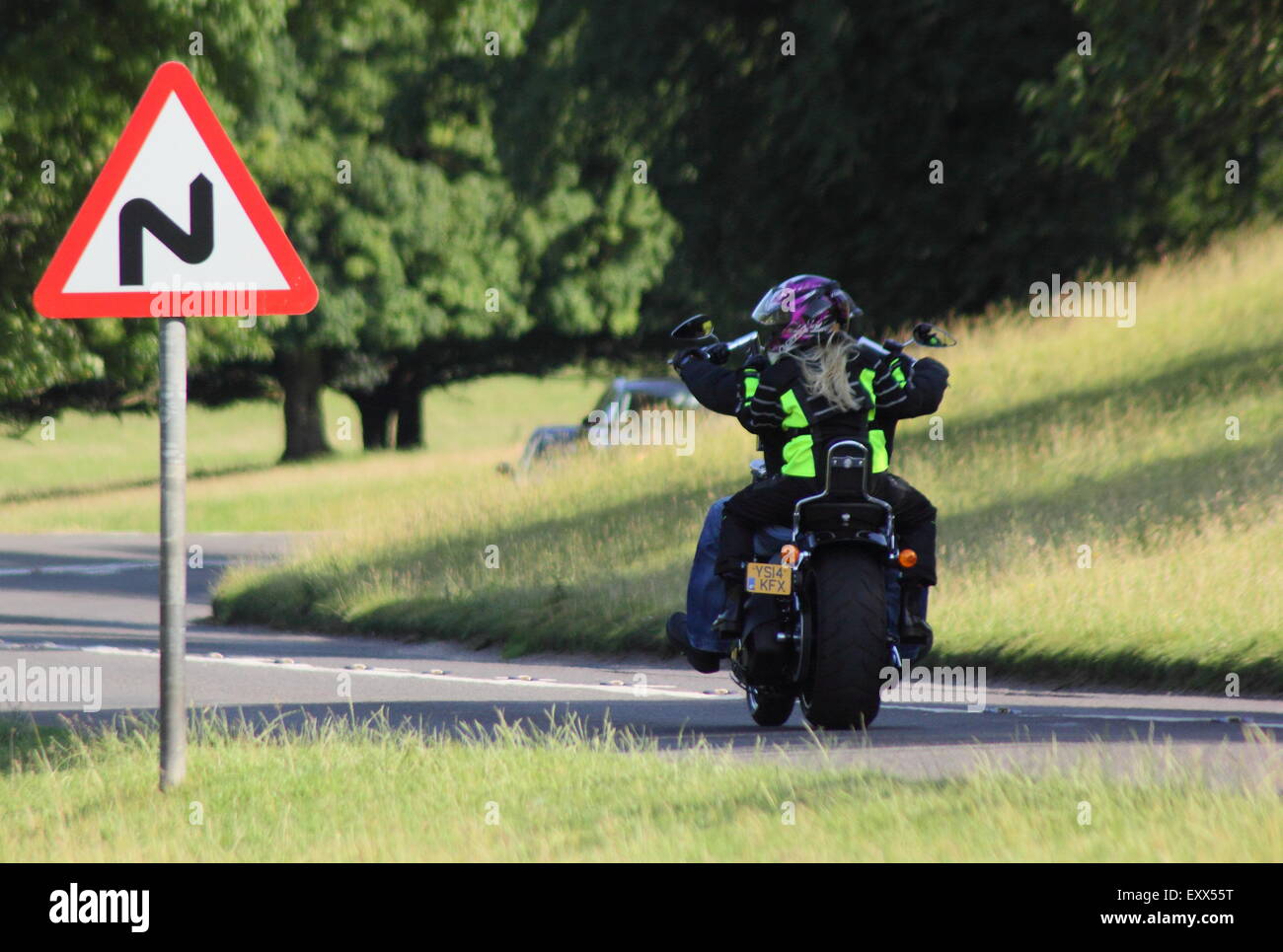A motorcyclist approaches a bend in a road in the Peak District, Derbyshire England UK Stock Photo