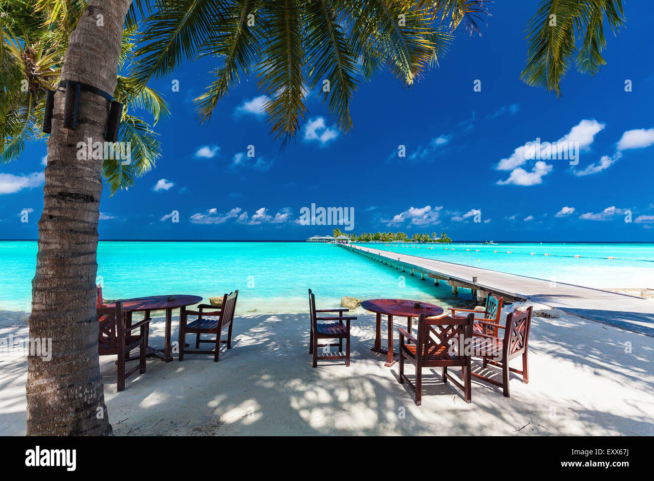 Tables and chairs in the shadow of palm tree on amazing tropical island