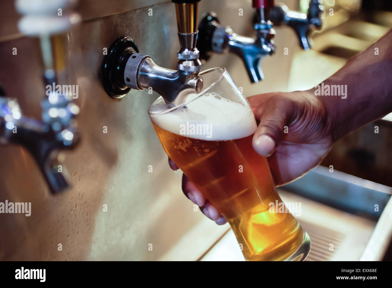 African American bartender filling beer glass from a bar tap Stock Photo