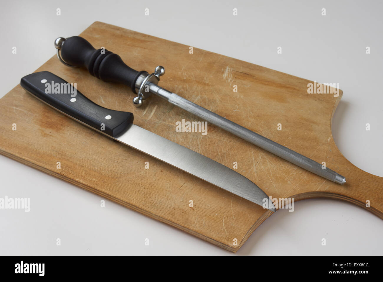 Knife with knife sharpener on wooden cutting board Stock Photo