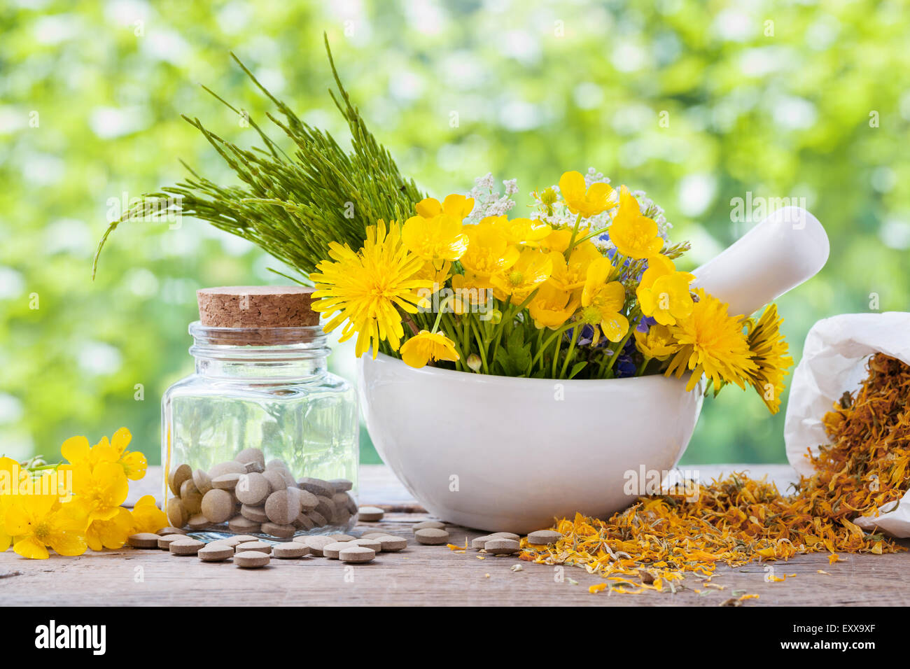 Healing herbs in mortar and bottle of pills on rustic table, herbal medicine. Stock Photo