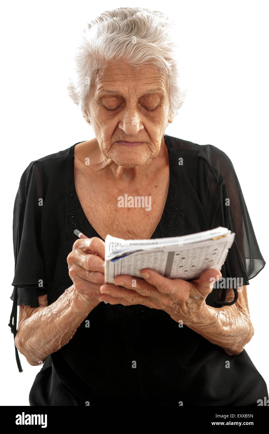 Concentrated elderly doing crossword . Stock Photo