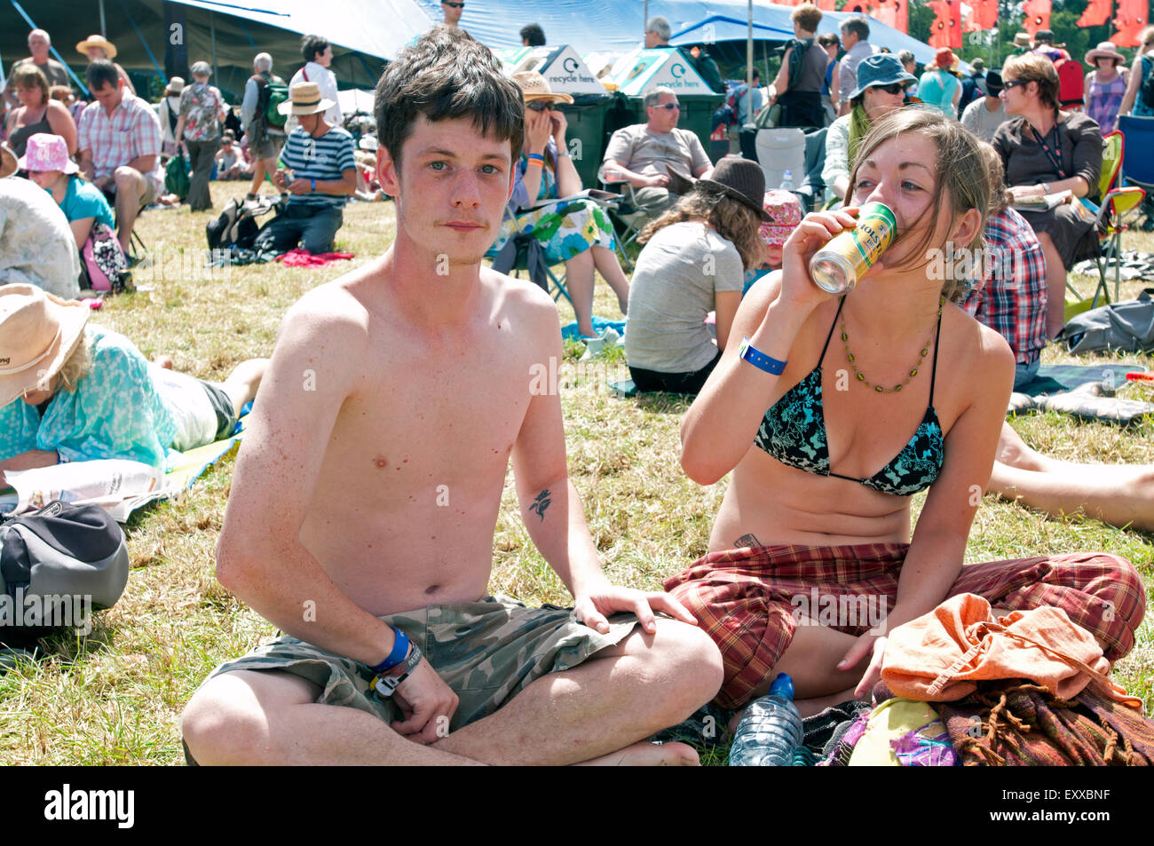 Two young hippies sit cross legged amongst the crowd at the WOMAD world music festival Stock Photo