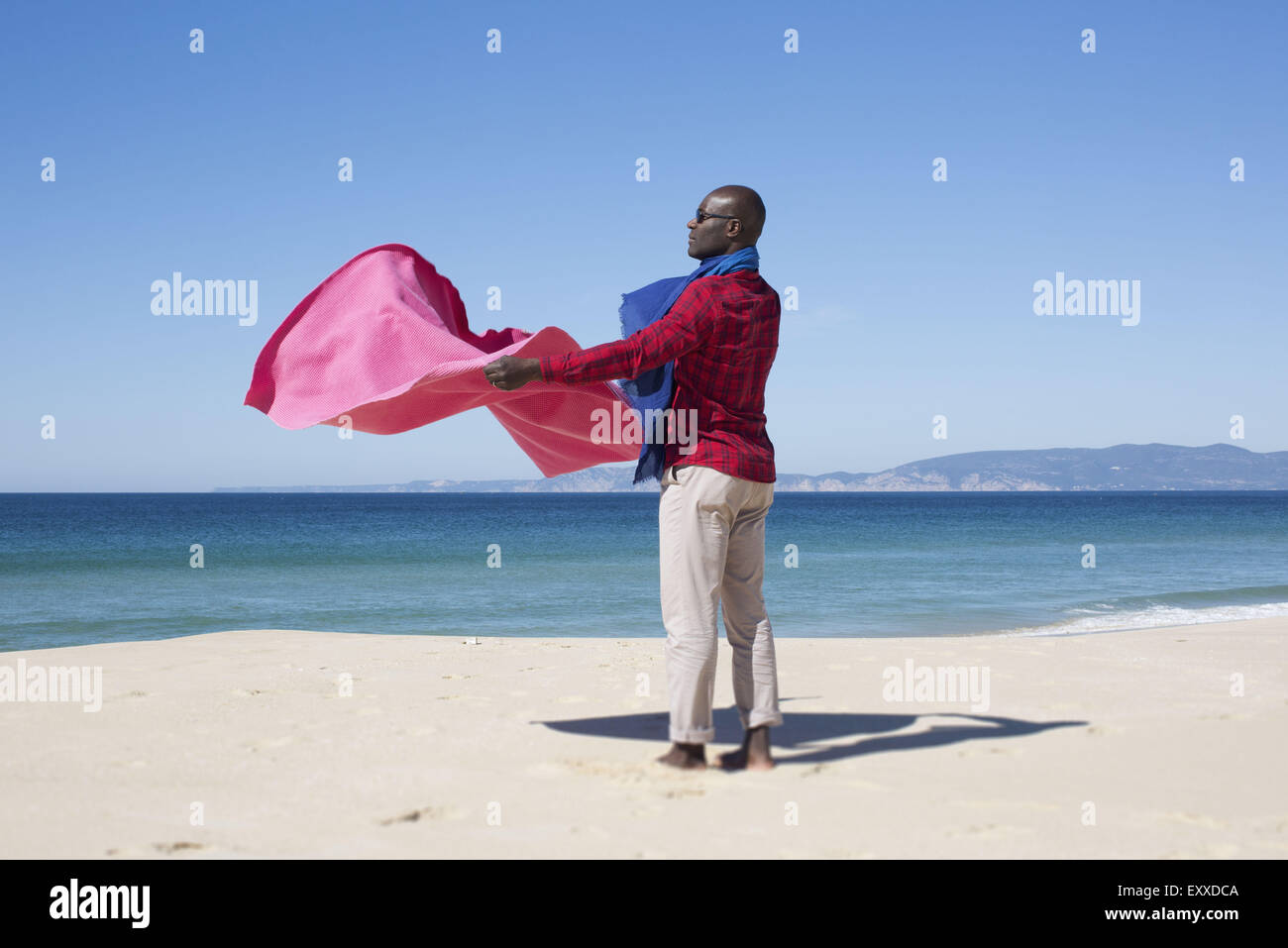 Man at the beach, holding blanket in the breeze Stock Photo