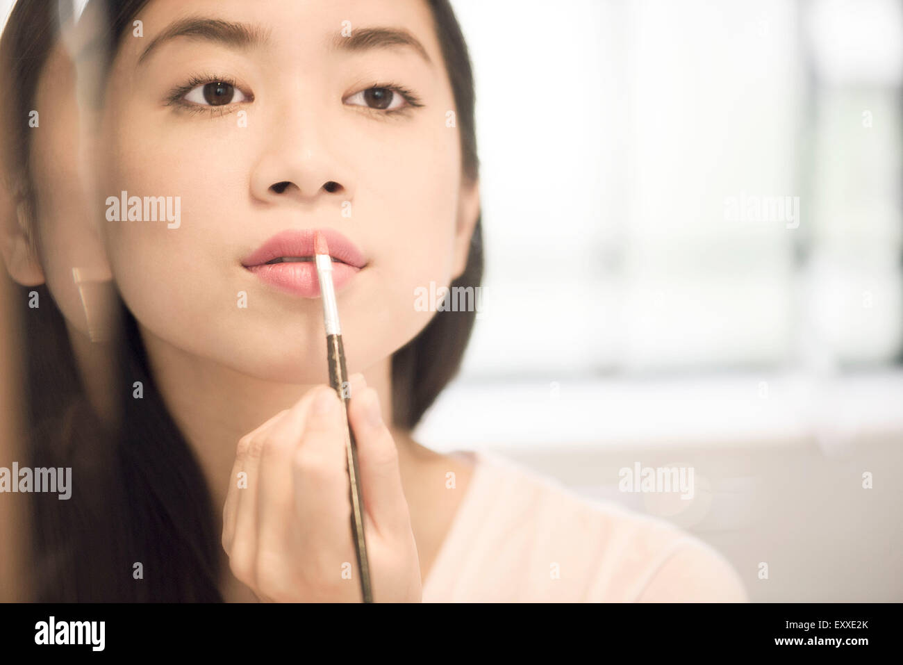 Woman using lipbrush to apply lipstick Stock Photo