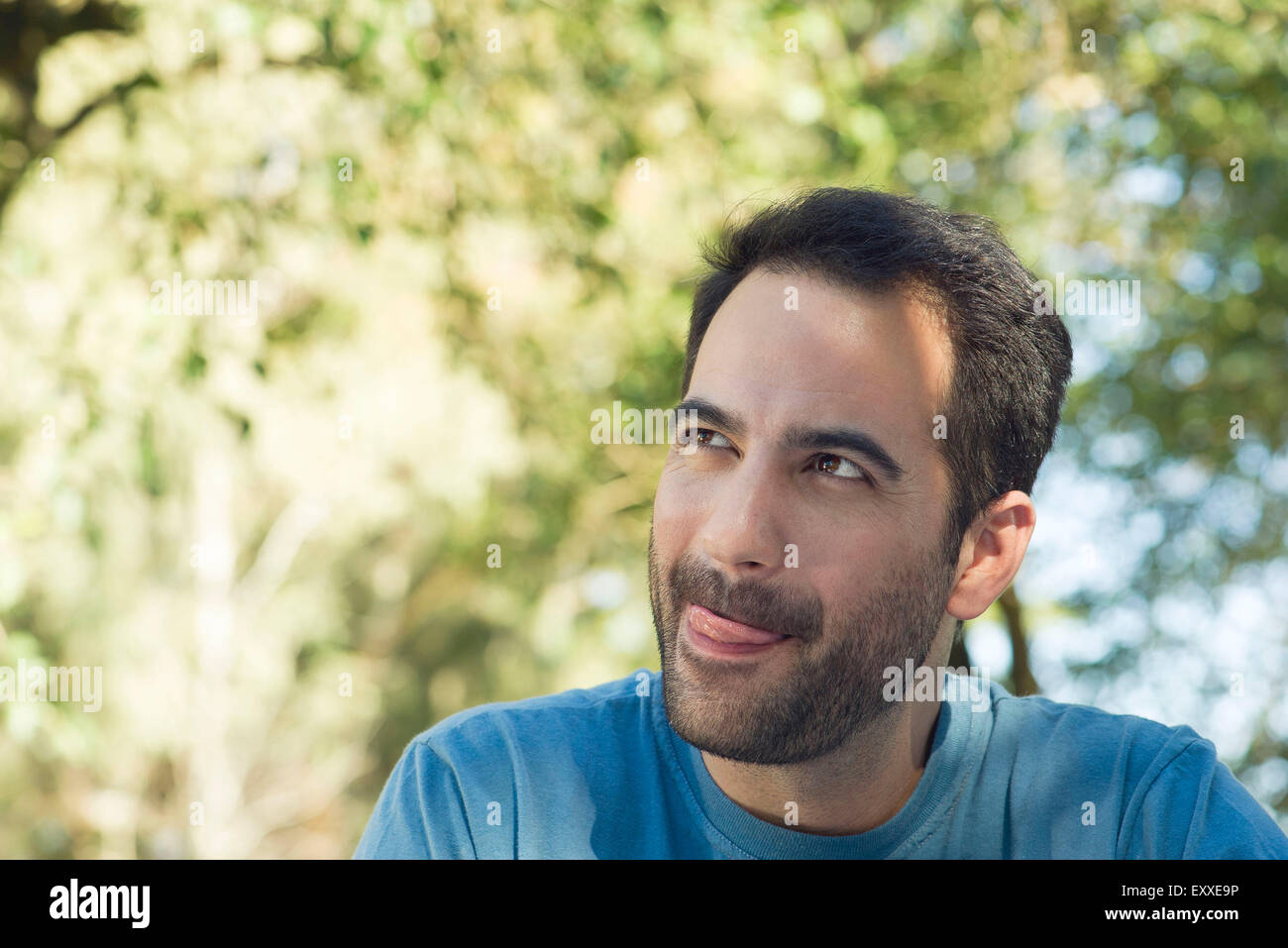 Man licking lips, daydreaming outdoors Stock Photo
