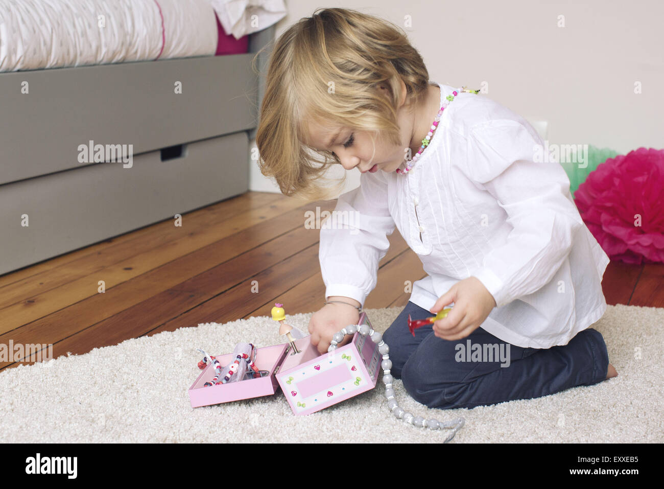 Little girl removing necklace from jewellery box Stock Photo